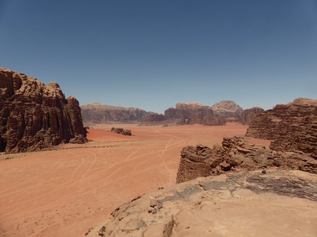 View of a wide desert valley in Wadi Rum with rock formations on all sides