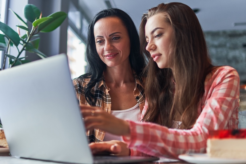 Smiling mother and daughter looking at something on a laptop together