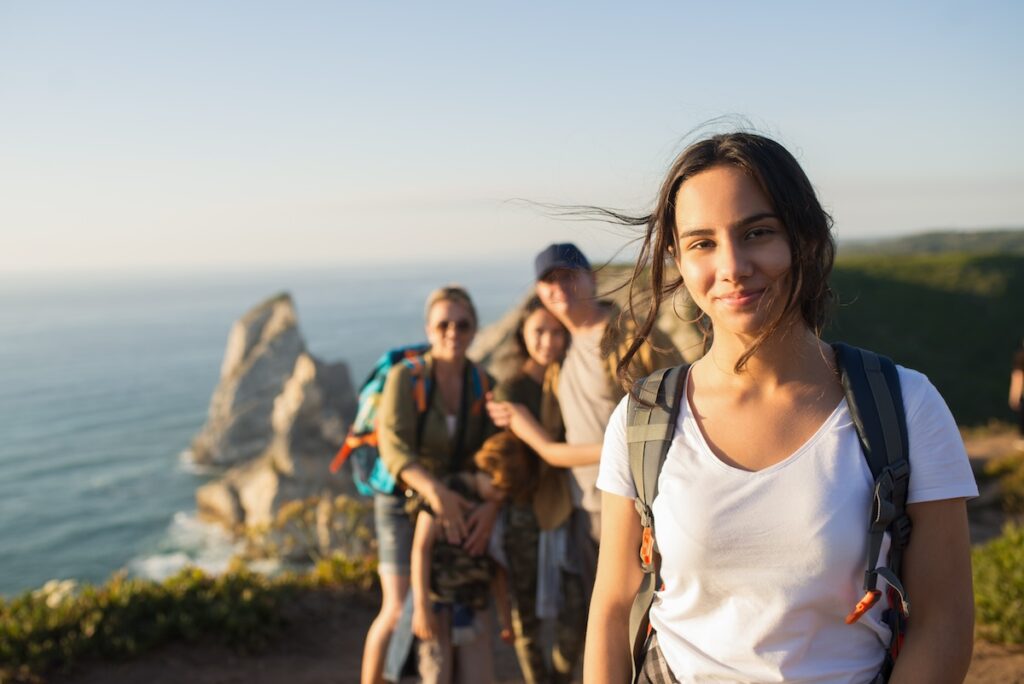 Picture of a girl in the foreground and a family in the background on a trip near the sea